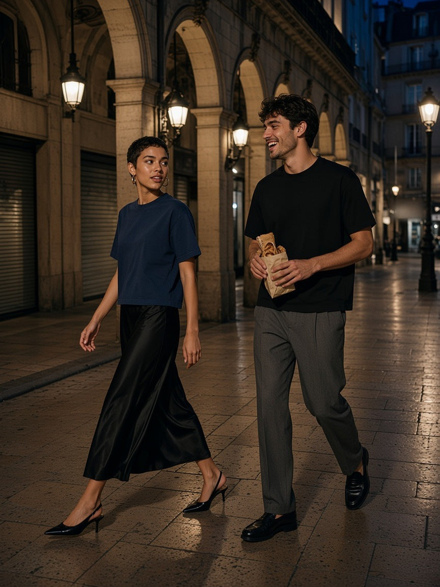 Woman and man in the Vintage Wash Sunfade Boxy T-Shirt in Navy Blue and Black walking under Haussmann arcades in Paris at night