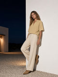 Woman in the Vintage Wash Waffle Boxy Polo Shirt in Khaki against a desert house wall in Marfa at night