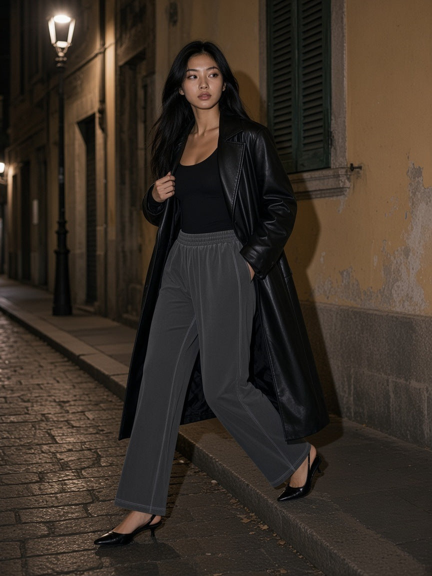 Woman in the Vintage Wash Wide Leg Mesh Sweatpants in Dark Gray with a black bodysuit, leather coat and kitten heels, stepping off a kerb on a Milan side street at night