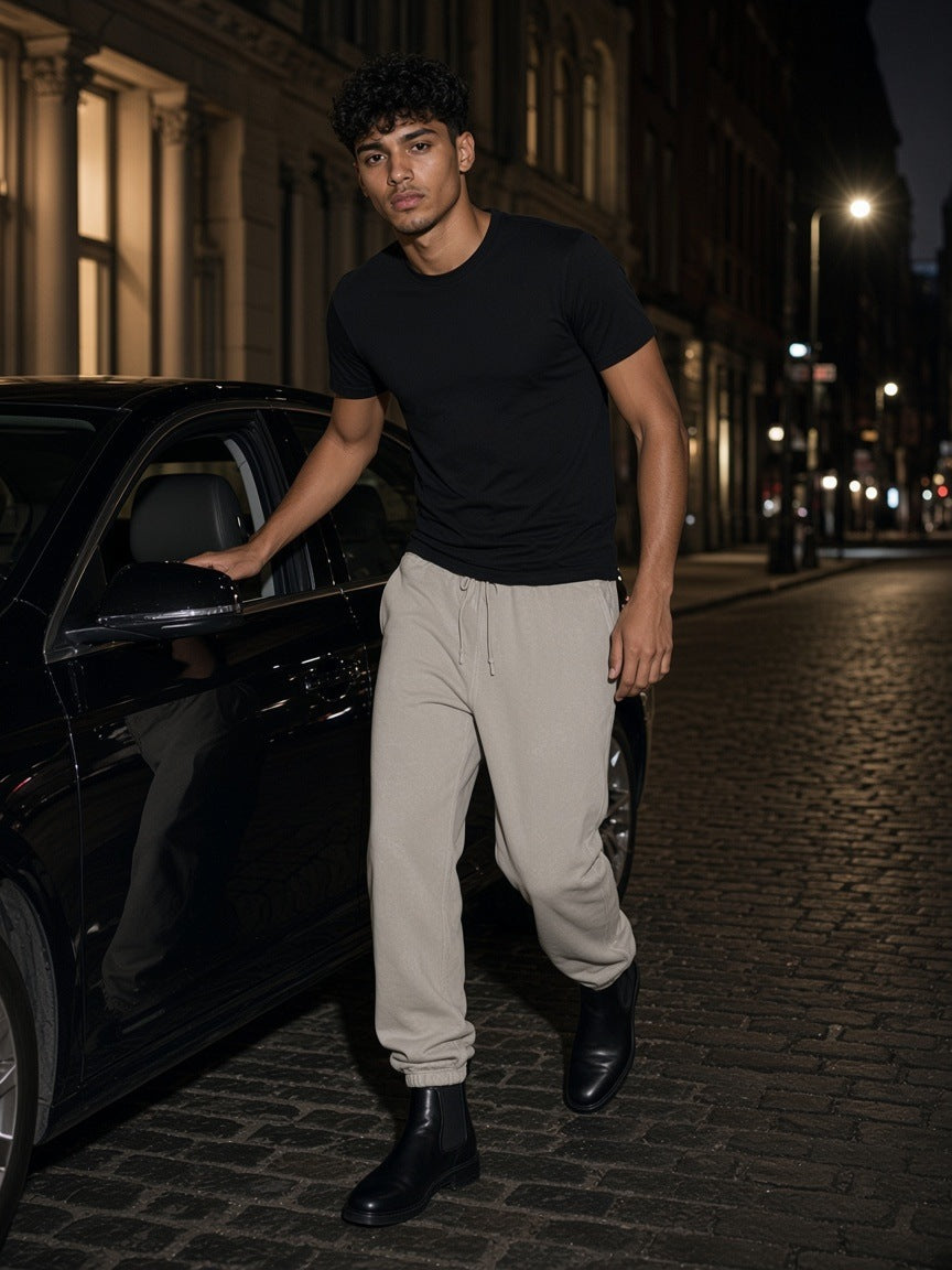 Man in the Vintage Washed Fleece Jogger Sweatpants in Light Gray walking past a black car on a SoHo street, New York at night