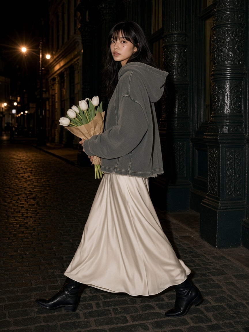 Woman in the Vintage Washed Frayed-Hem Hoodie in Gray with an ivory silk maxi skirt and ankle boots, carrying tulips down a cobbled Brussels street at night