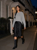 Woman in the Vintage Washed Long Sleeve T-Shirt in Medium Gray walking past stucco townhouses in Belgravia, London at night