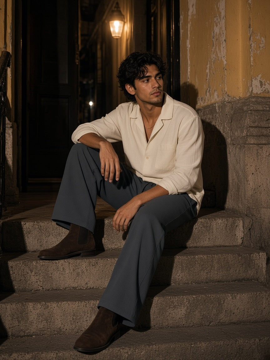 Man in the Waffle Barrel Leg Pants in Dark Gray with a cream camp-collar shirt, sitting on a colonial doorstep in Mexico City at night