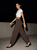Woman in the Waffle Barrel Leg Pants in Coffee striding through a concrete courtyard in Marfa, Texas at night