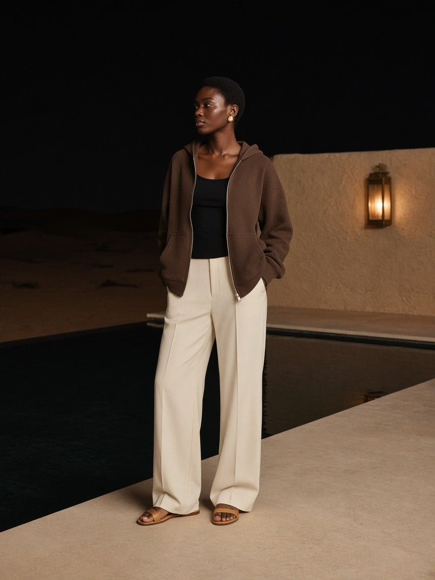 Woman in the Marcel Afters Waffle Boxy Full Zip Hoodie in Coffee beside an infinity pool at a desert resort outside Dubai at night