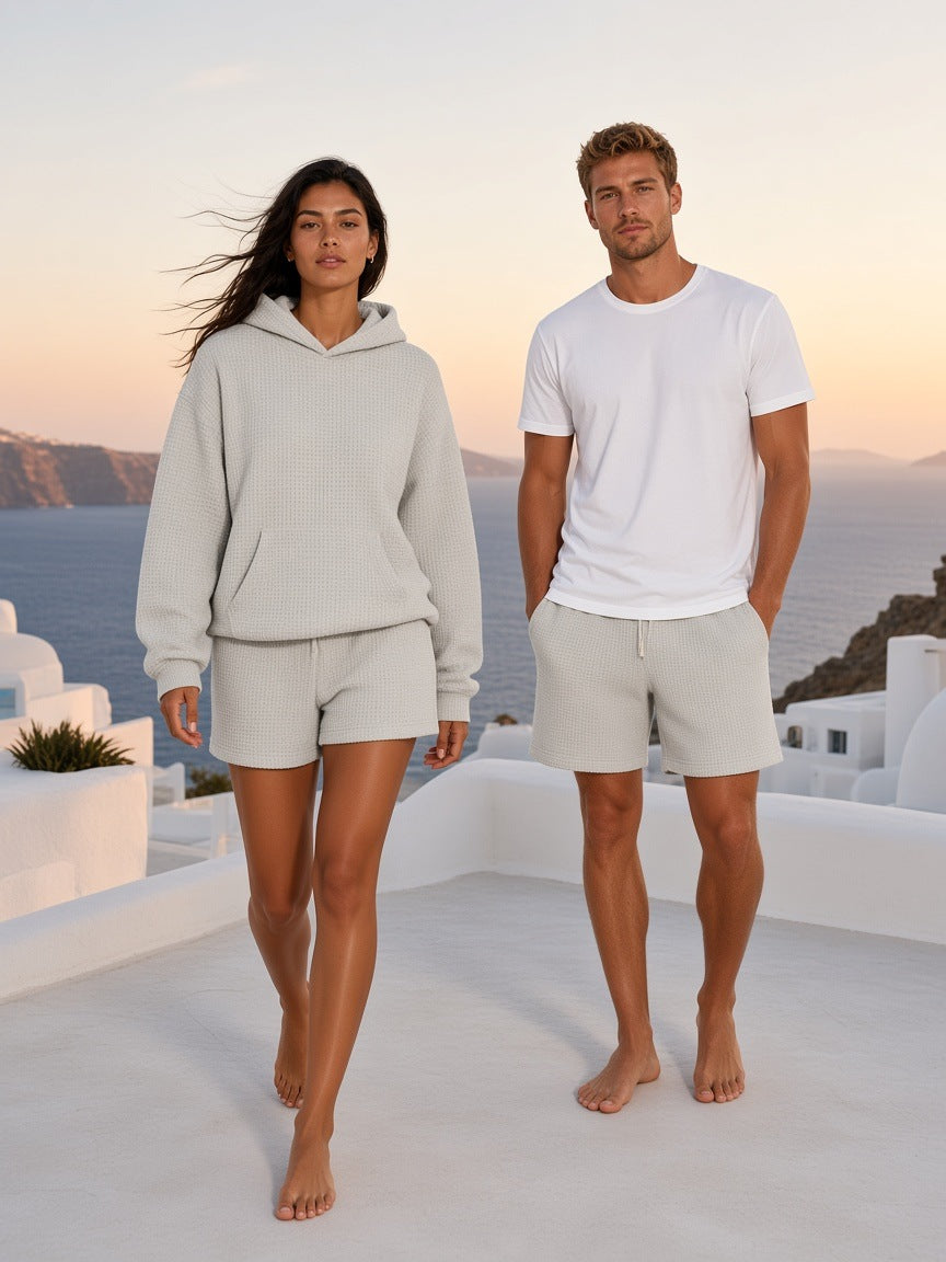 Two people in the Marcel Afters Waffle Boxy Hoodie in Oat Gray and a white tee, barefoot on a whitewashed terrace in Mykonos at dusk