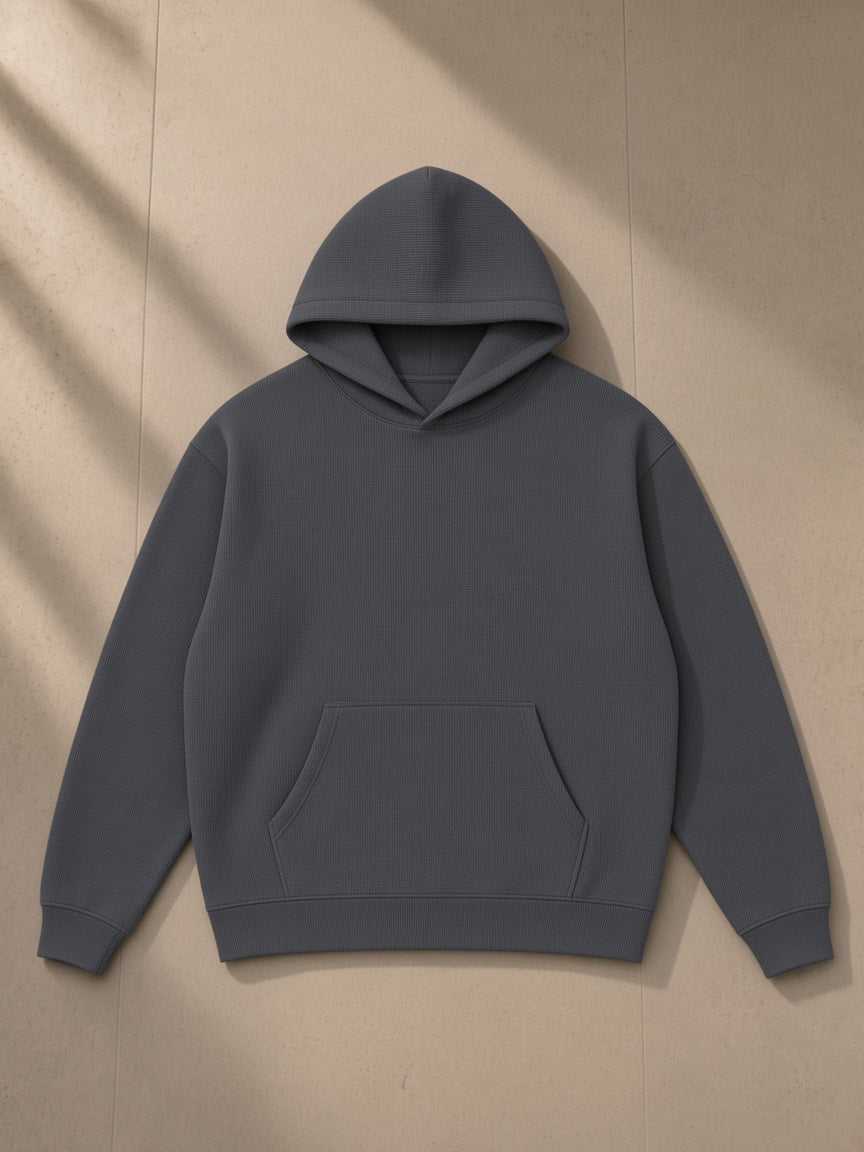 Waffle Hoodie in Dark Gray, laid flat on pale limestone, front view