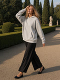 Woman in the Waffle Hoodie in Oat Gray with black wide trousers and ballet flats, laughing on a gravel walk in the Boboli Gardens, Florence by day
