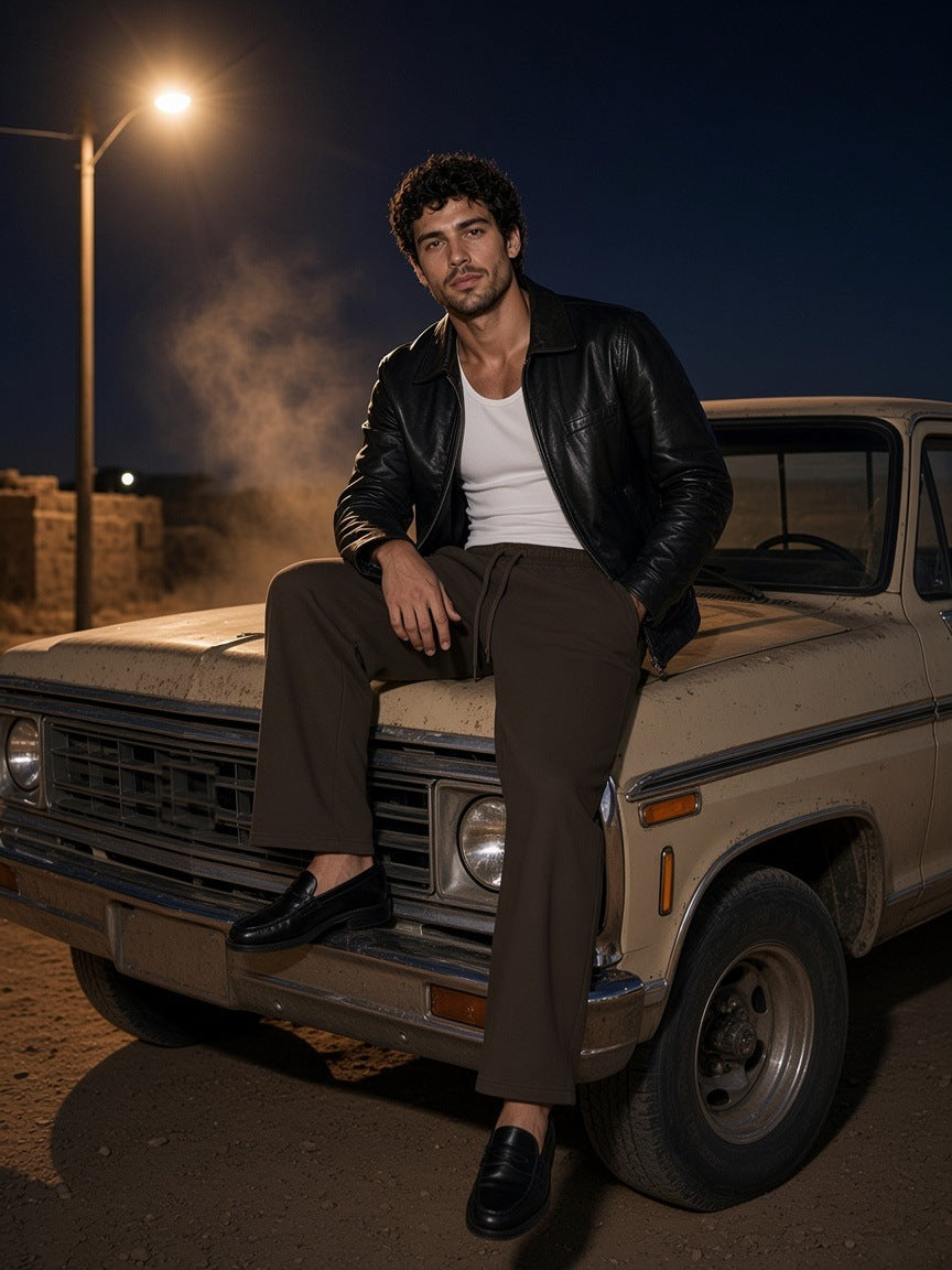 Man in the Wide Leg Drawstring Sweatpants in Brown leaning on an adobe wall in Marfa, Texas at night