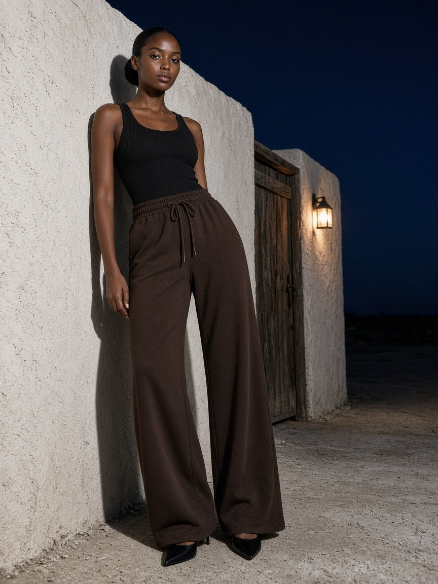 Woman in the Wide Leg Drawstring Sweatpants in Brown leaning on an adobe wall in Marfa, Texas at night