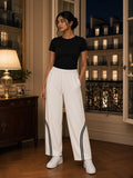 Woman in the Wide Leg Piping Sweatpants in White by the open windows of a Paris hotel suite at night