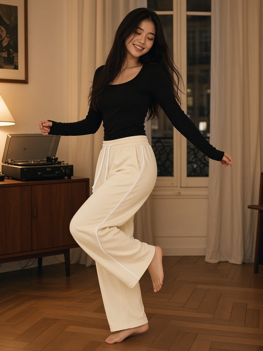 Woman in the Wide Leg Piping Sweatpants in Apricot dancing barefoot on a parquet floor in a Paris apartment