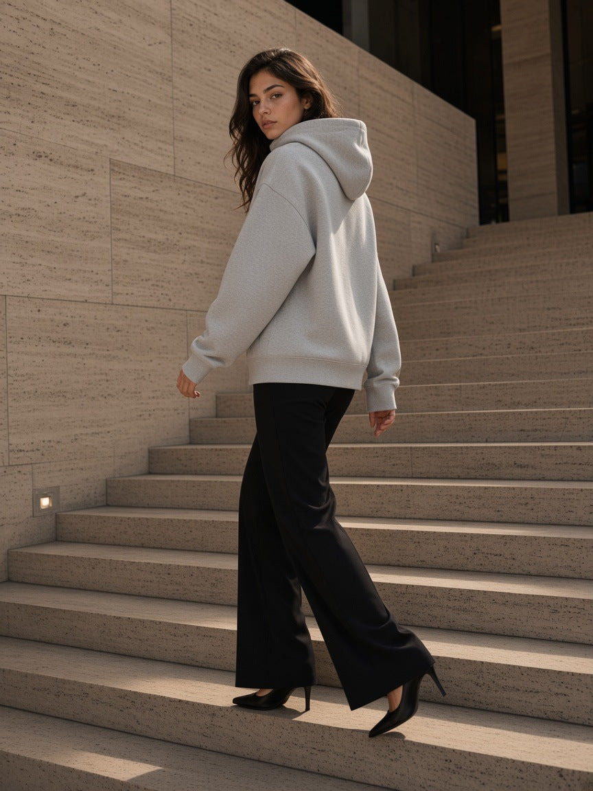 Woman in the Women's Essential Heavyweight High Neck Zip-Up Hoodie in Flower Gray with black flares, descending a travertine stair in Milan by day