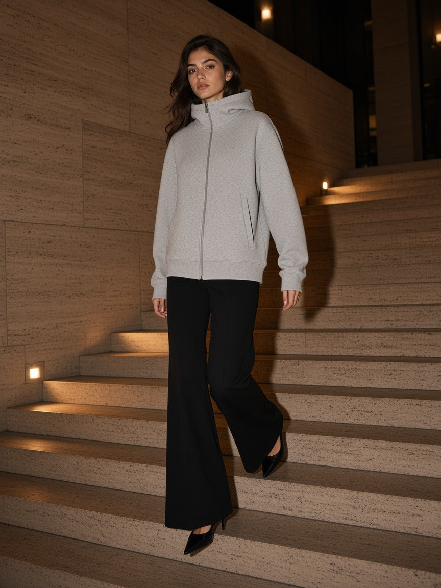 Woman in the Marcel Afters Women's Essential Heavyweight High Neck Zip-Up Hoodie in Flower Gray with black flares, descending a travertine stair in Milan at night