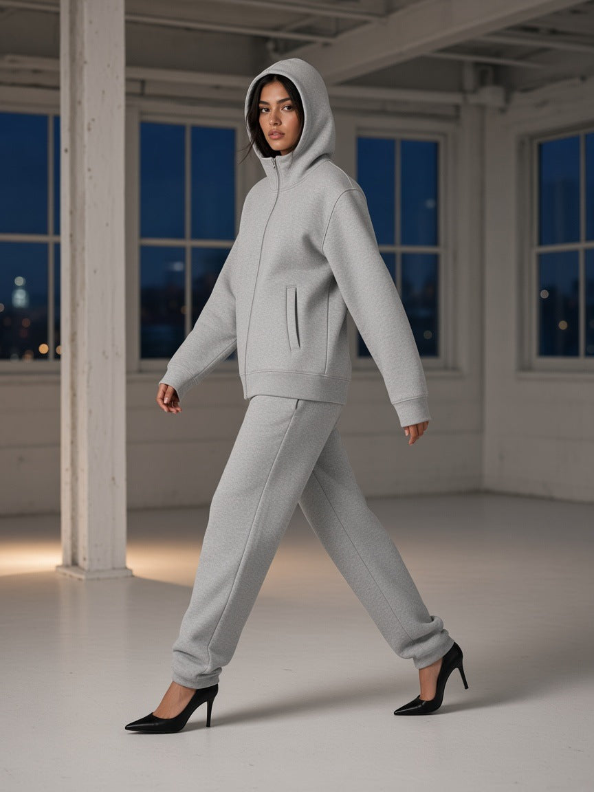 Woman in the Women's Essential Heavyweight High Neck Zip-Up Hoodie in Flower Gray, hood up, walking in heels through an empty SoHo loft in New York