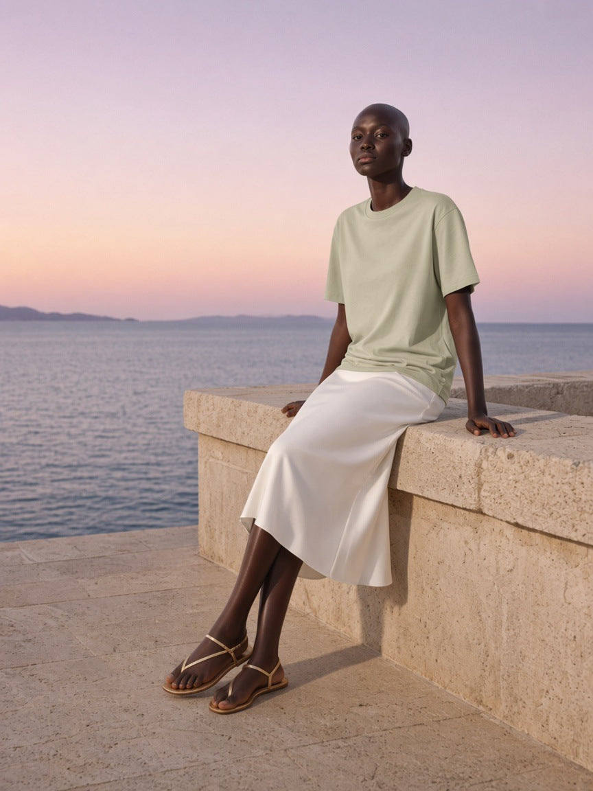 Woman in the Women's Heavyweight Earth Tone T-Shirt in Sand Color on a limestone sea terrace in Sicily at dusk