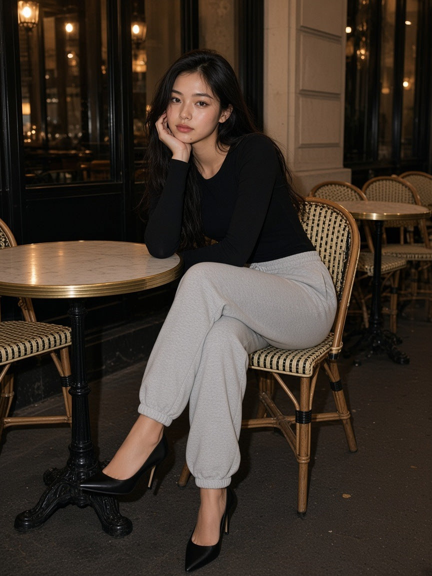 Woman in the Women's Heavyweight Fleece Joggers in Flower Gray at a café table on a terrace in Paris at night