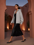 Woman in the Women's Heavyweight Full Zip Boxy Hoodie in Flower Gray over a black slip dress, walking through a pink plaster riad arch in Marrakech