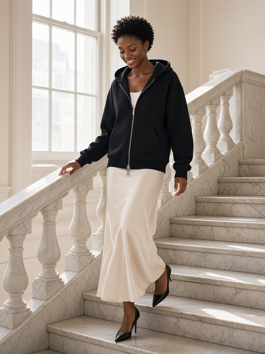Woman in the Women's Heavyweight Full Zip Hoodie in Black walking through a marble hotel lobby on the Upper East Side, New York in the morning