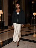 Woman in the Women's Heavyweight Full Zip Hoodie in Black walking through a marble hotel lobby on the Upper East Side, New York at night