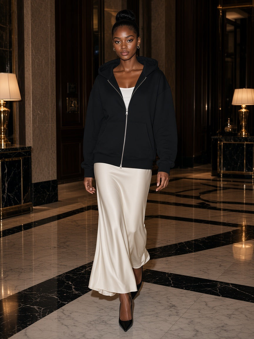 Woman in the Women's Heavyweight Full Zip Hoodie in Black walking through a marble hotel lobby on the Upper East Side, New York at night