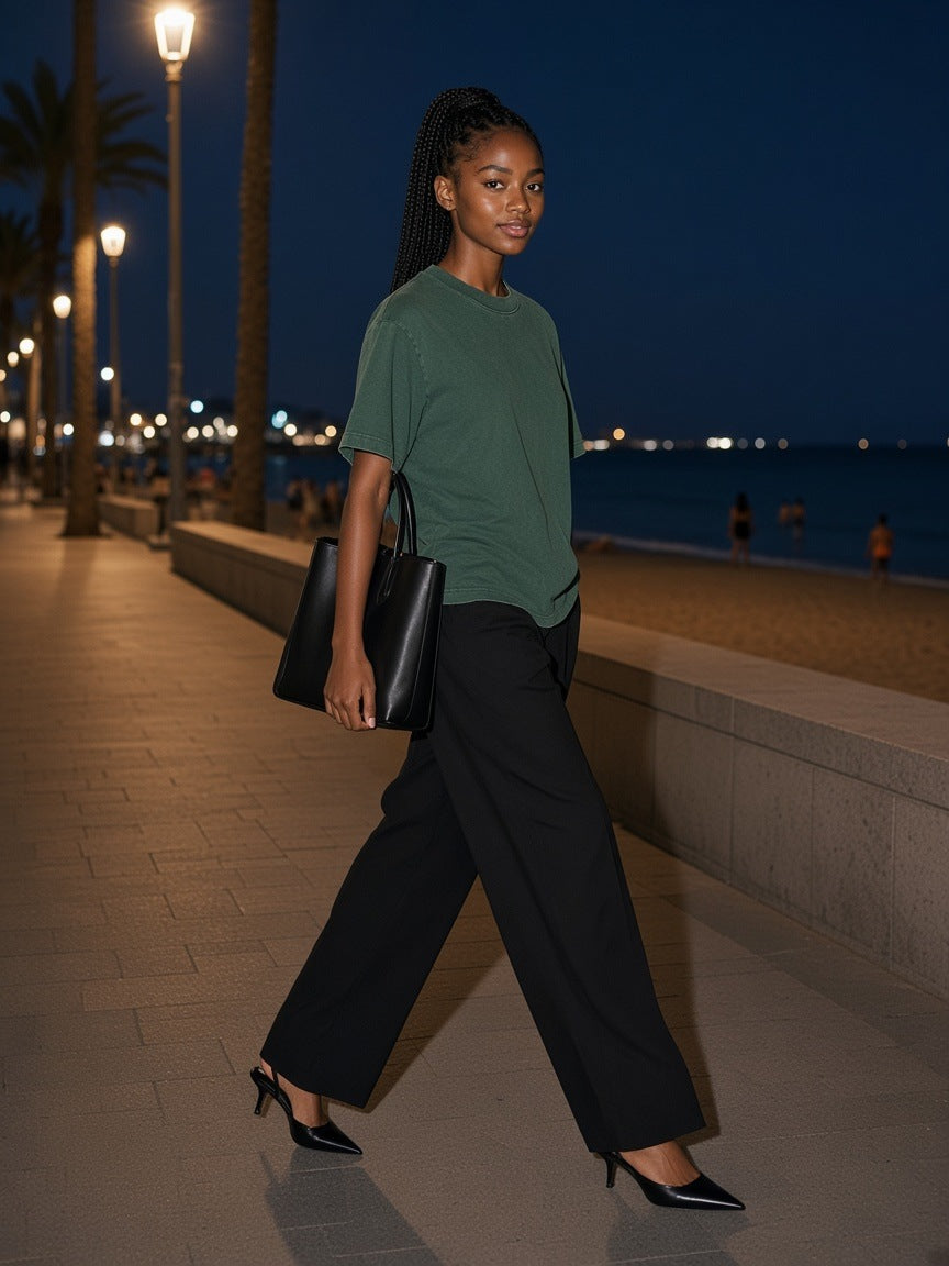 Woman in the Women's Heavyweight Vintage Washed Frayed T-Shirt in Retro Green walking the Barceloneta boardwalk in Barcelona at night