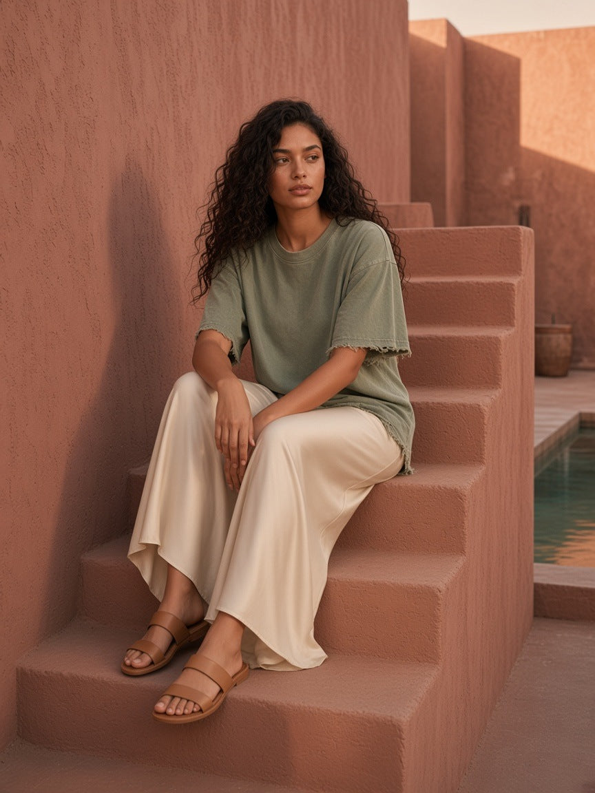 Woman in the Women's Heavyweight Vintage Washed Frayed T-Shirt in Gray Green on a pink plaster riad stair in Marrakech at golden hour by day