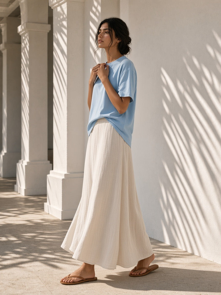 Woman in the Women's Oversized T-Shirt in Sky Blue under a palm-shaded plaster colonnade at a resort in the morning
