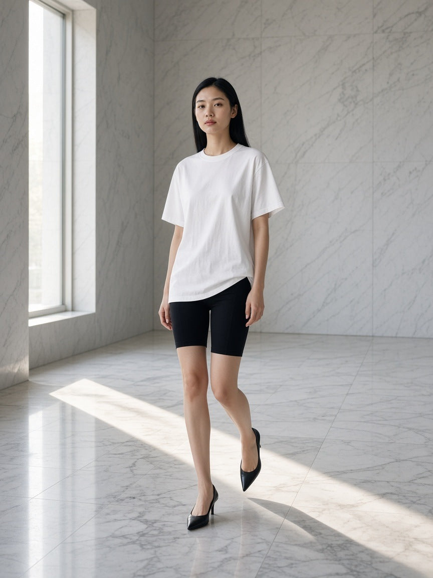 Woman in the Women's Oversized T-Shirt in White in an empty marble hotel lobby at dawn
