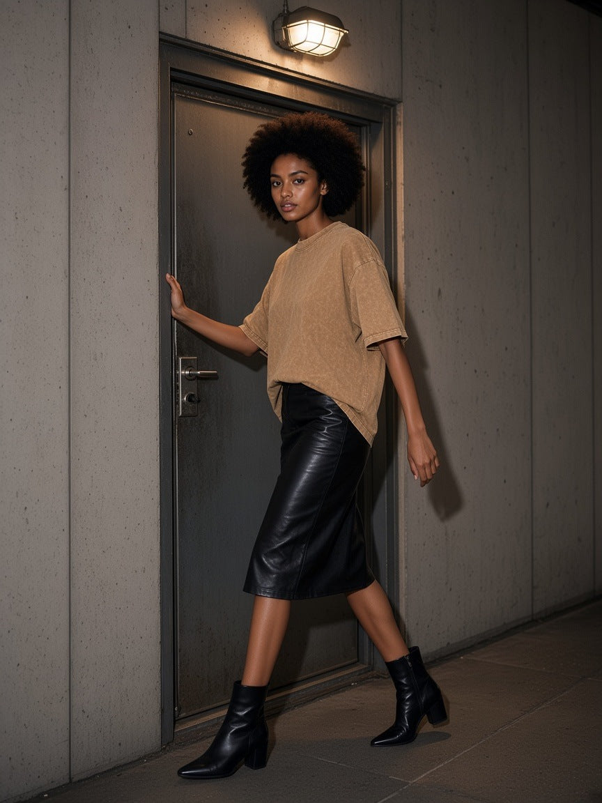Woman in the Women's Snow Washed Heavyweight Oversize T-Shirt in Camel pushing through a steel door at the Leake Street tunnel exit in London at night