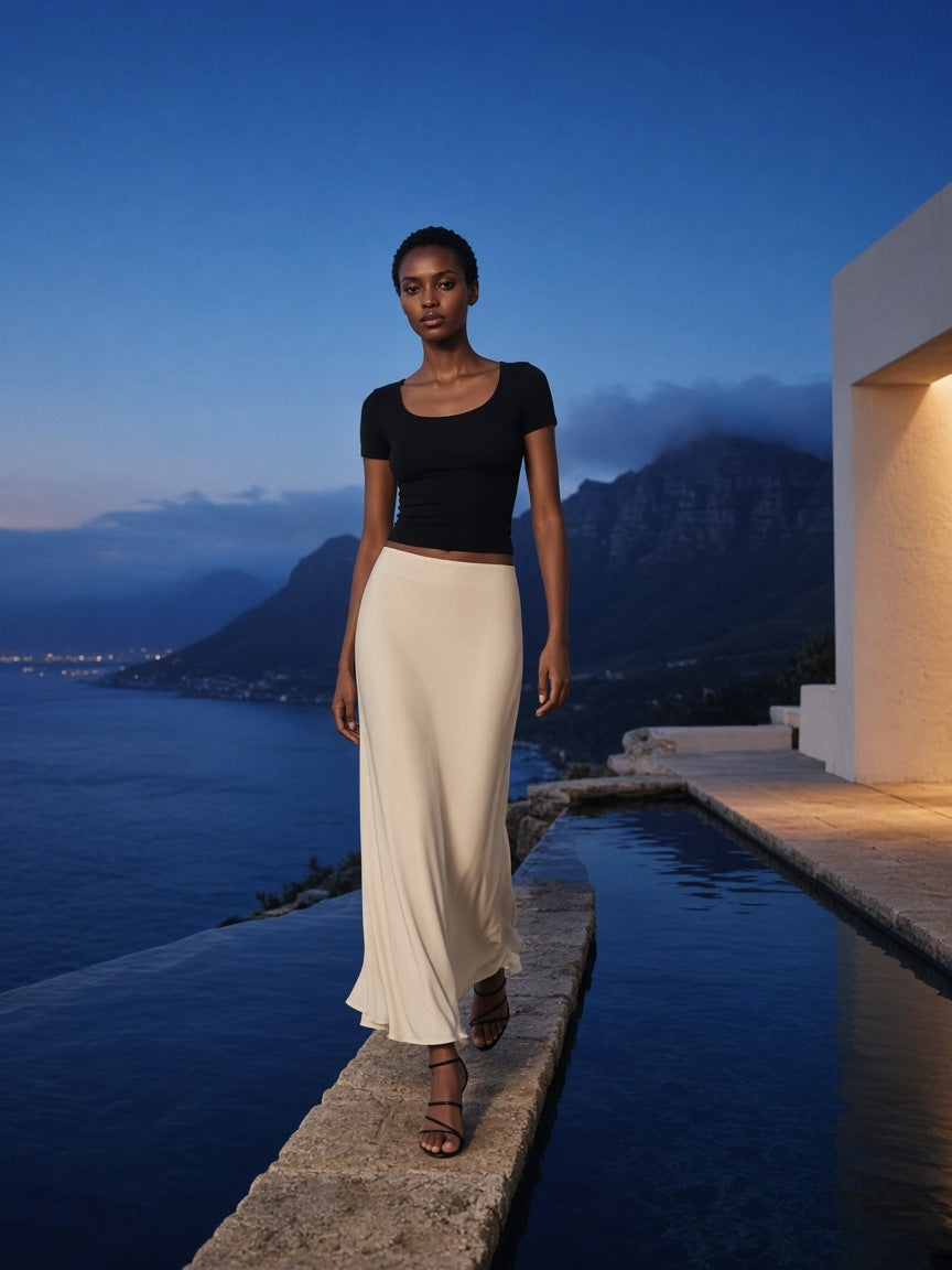 Woman in the Marcel Afters Women's Solid Color Slim Crop T-Shirt in Black at a clifftop infinity pool in Cape Town at blue hour