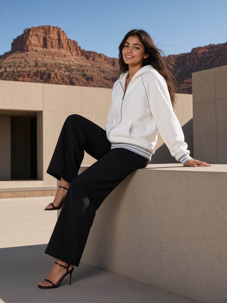 Woman in the Women's Striped Trim Zip-Up Hoodie in White, walking in heels across a desert-modern concrete courtyard in Amangiri, Utah by day