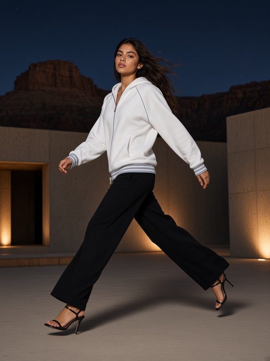 Woman in the Women's Striped Trim Zip-Up Hoodie in White, walking in heels across a desert-modern concrete courtyard in Amangiri, Utah at night