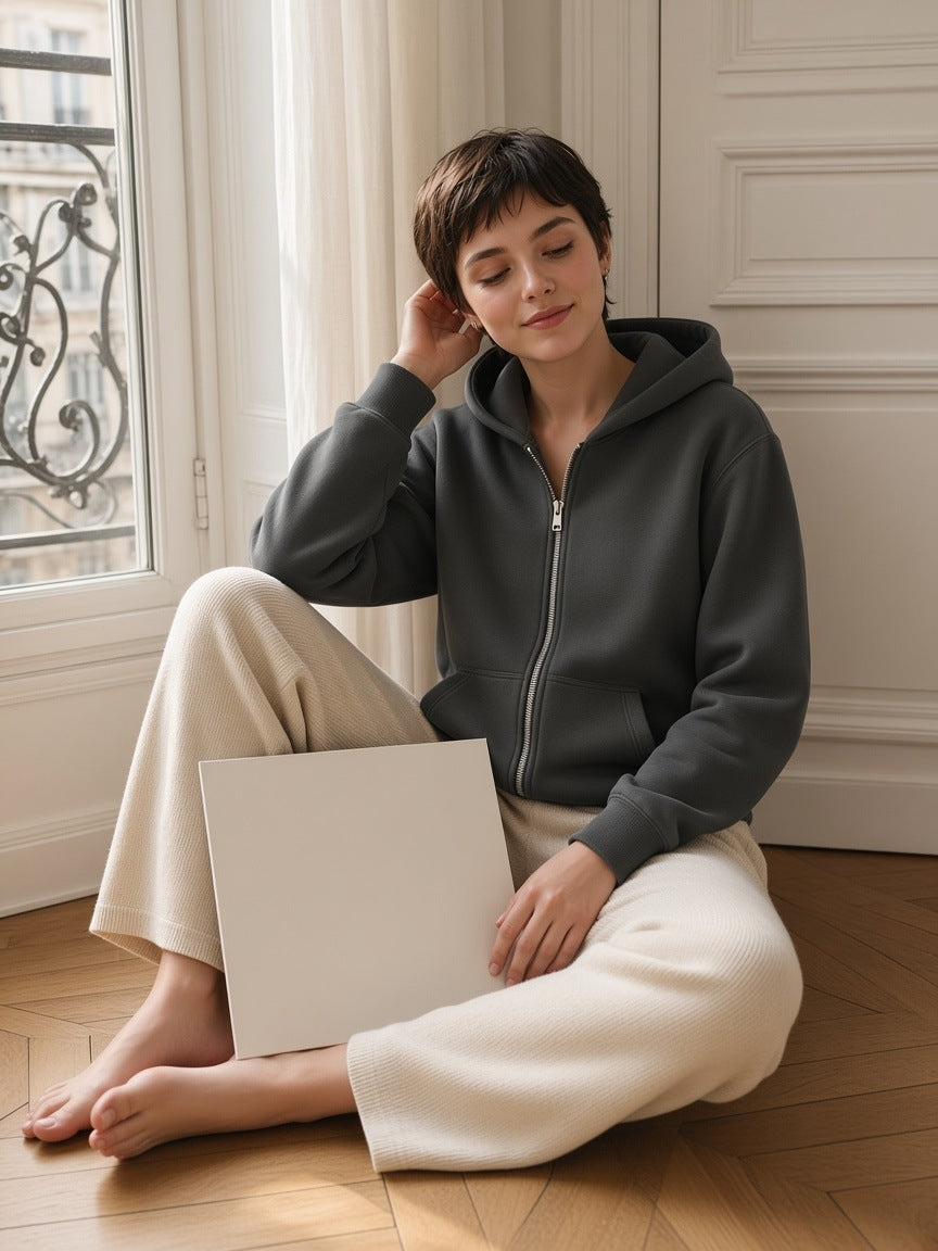 Woman in the Women's Heavyweight Full Zip Hoodie in Dark Gray on the parquet of a sunlit Paris apartment
