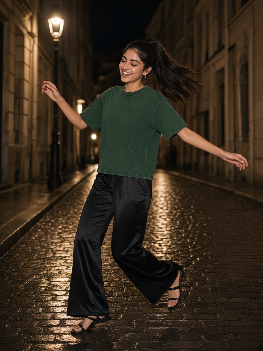 Woman in the Women's Heavyweight Mineral Wash Boxy T-Shirt in Dark Green spinning on a cobbled Paris street at night