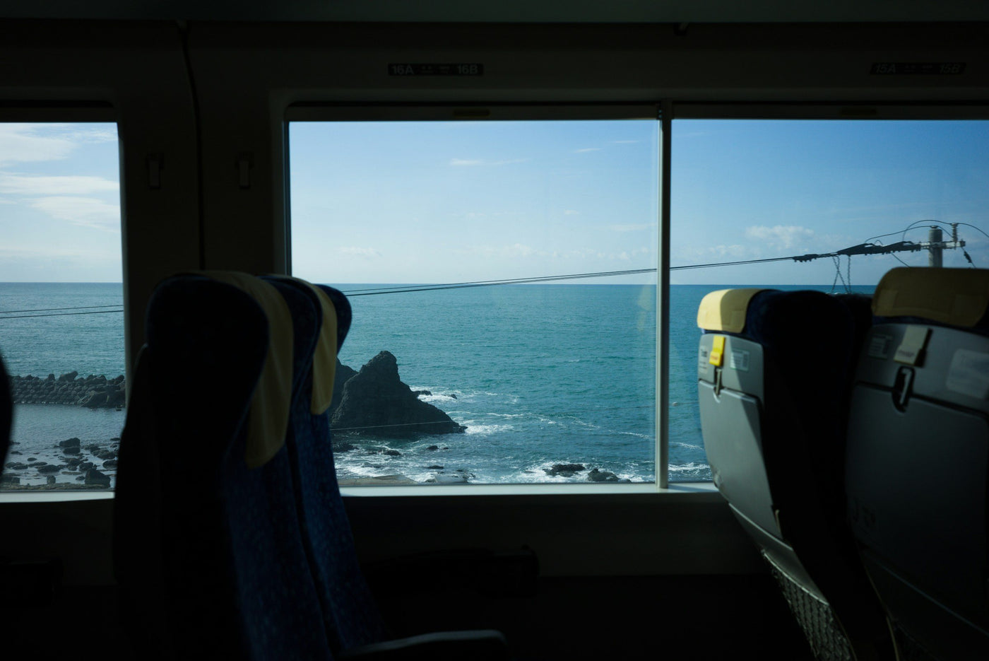 The sea from a train window, seats in shadow.